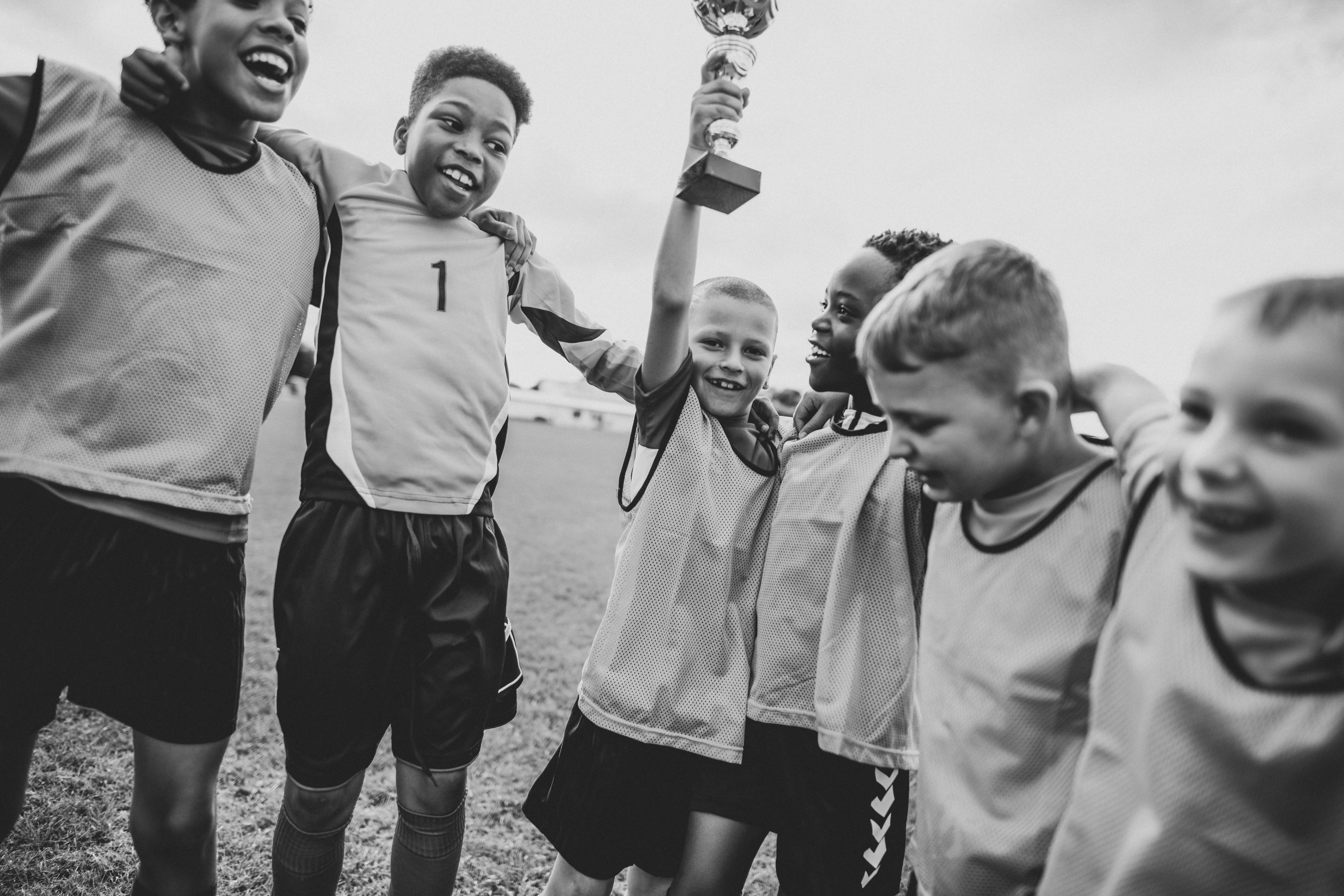 Black and white photograph if young kids on the field celebrating their victory. Youth sports teams can benefit from fireworks fundraisers.